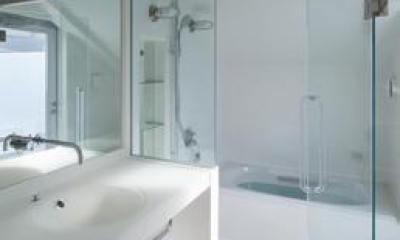 真っ白な空間の洗面コーナーとバスルーム｜阿倍野の家