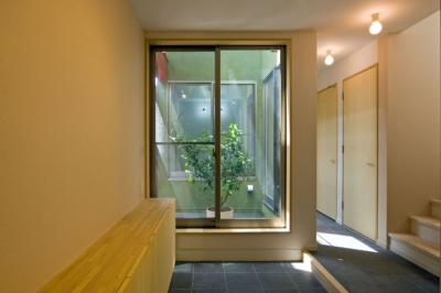 ライトコートに接する玄関の土間スペース (陽が降り注ぐライトコートのある家/東京都阿佐ヶ谷の家)