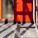 木格子の家／石神井台の二世帯住宅の写真 炭入りモルタルの床面とベンガラ塗装の玄関ドア