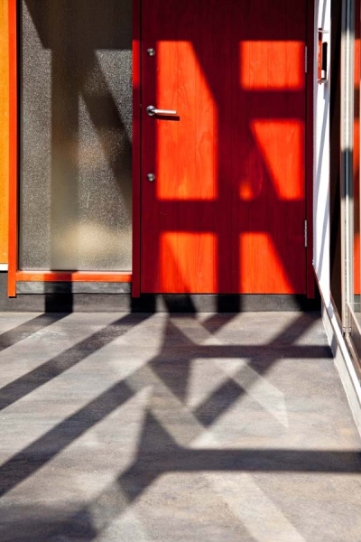炭入りモルタルの床面とベンガラ塗装の玄関ドア (木格子の家／石神井台の二世帯住宅)