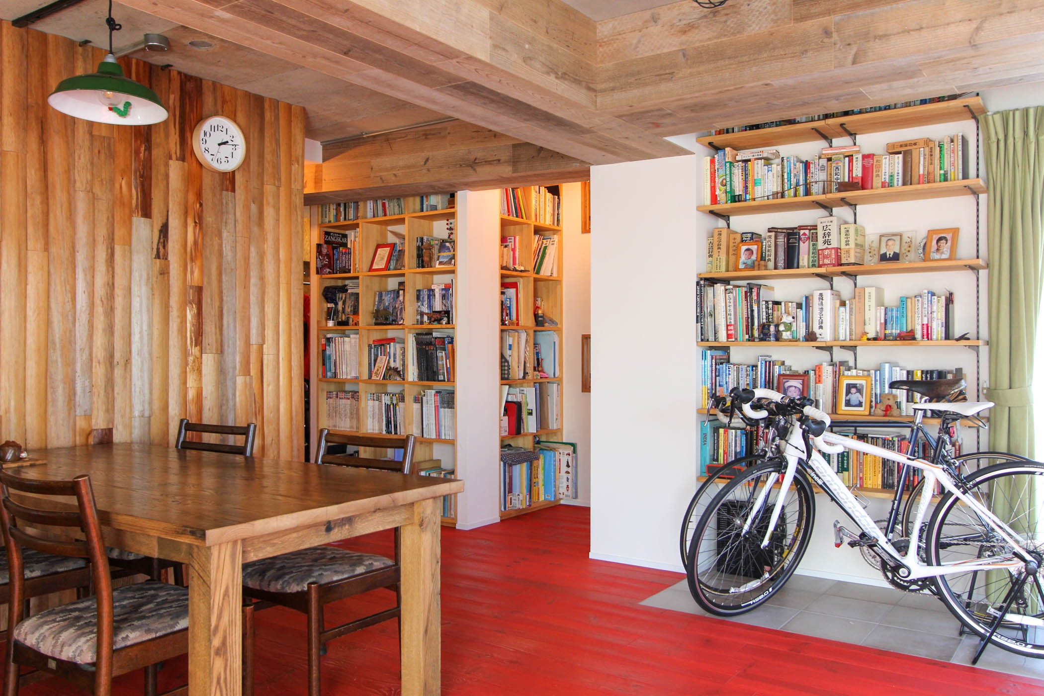 リビングダイニング事例：自転車と本棚と丸太の壁（赤い床の山小屋ハウス）