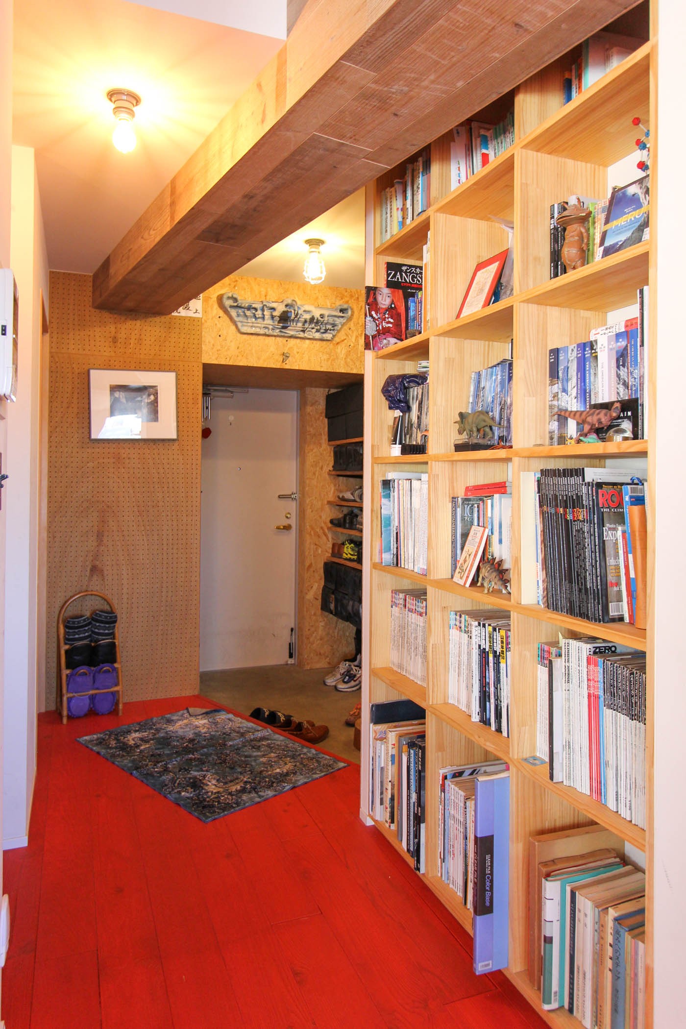 玄関事例：木製の本棚と玄関土間（赤い床の山小屋ハウス）