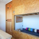 赤い床の山小屋ハウスの写真 木製扉とOSBボードのベッド