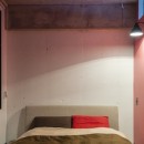 色で遊んだシックなお部屋の写真 ピンク壁が可愛く、リビングとの仕切りに窓を使用することで採光も良いベッドルーム