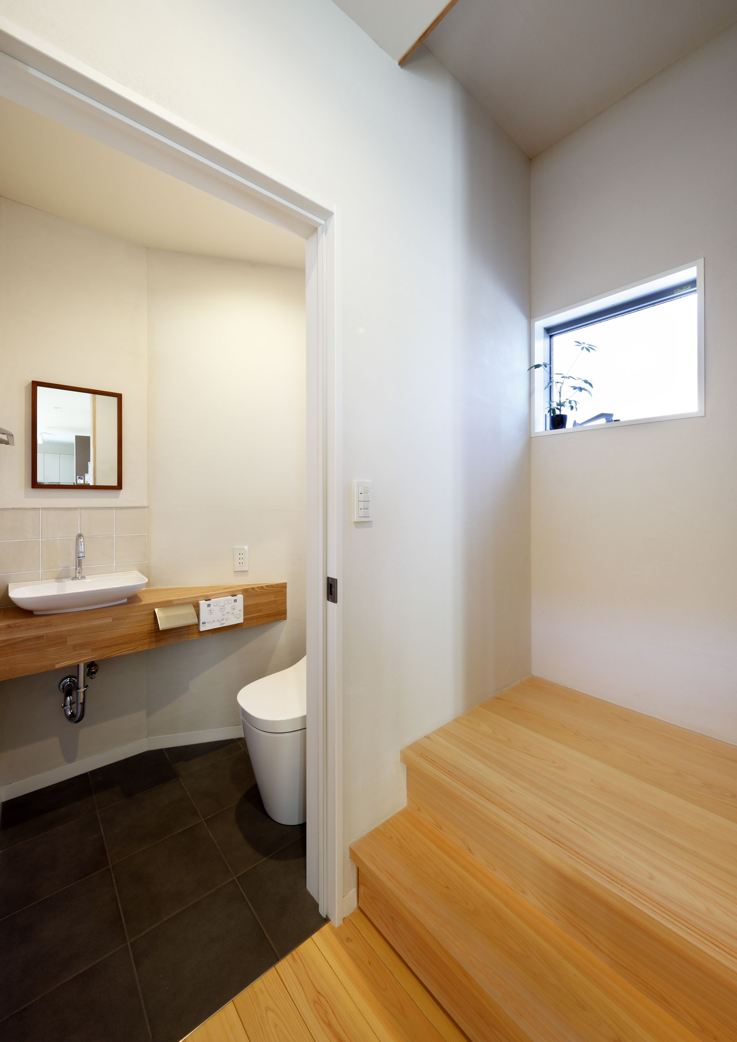 バス/トイレ事例：エントランスつながるヒノキの階段と横のお手洗い（「中庭のある無垢な珪藻土の家」）