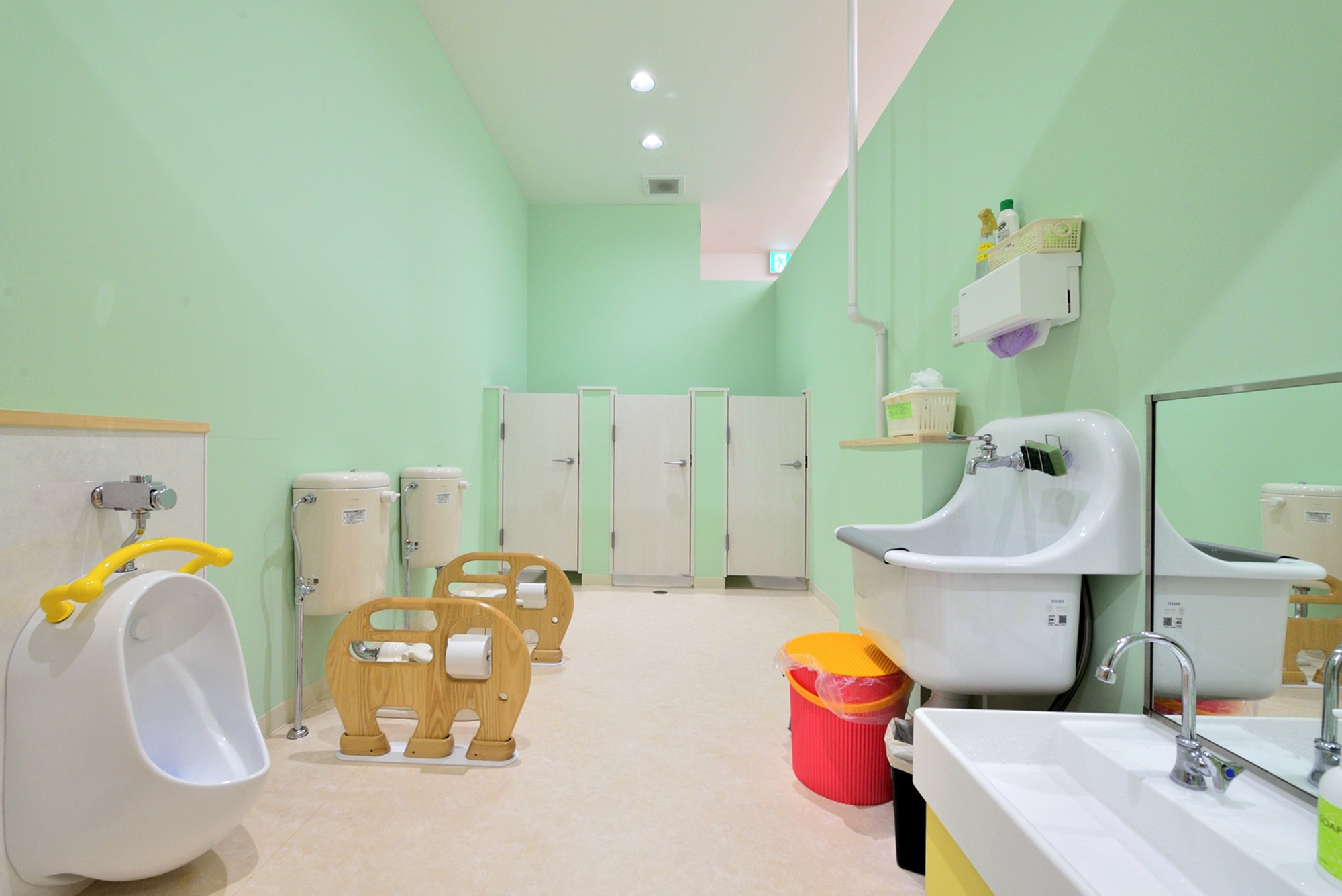 明るいグリーンの壁が特徴のトイレ(横須賀市 ～にじのそら保育園～) バス/トイレ事例｜SUVACO(スバコ)