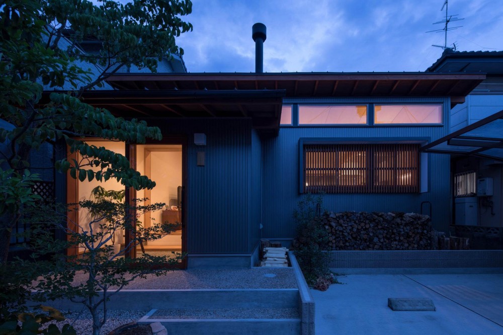 伊勢田の家／夫婦２人のためのコンパクトな平屋の住まい (外観の夕景／LDKの高窓と格子からも暖かい光が漏れています。)