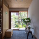 伊勢田の家／夫婦２人のためのコンパクトな平屋の住まいの写真 玄関／ガラス戸の向こうに前庭の緑が見えています。左側には衝立で仕切られたシューズクローク。