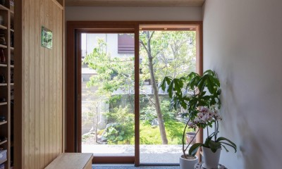 伊勢田の家／夫婦２人のためのコンパクトな平屋の住まい (玄関／ガラス戸の向こうに前庭の緑が見えています。左側には衝立で仕切られたシューズクローク。)