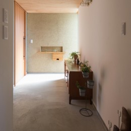 日吉台の家／大きな屋根の下にスキップフロアで各部屋が繋がる大らかな住まい-玄関／左官塗りの外壁や土間のモルタルに良く馴染む木製の玄関戸