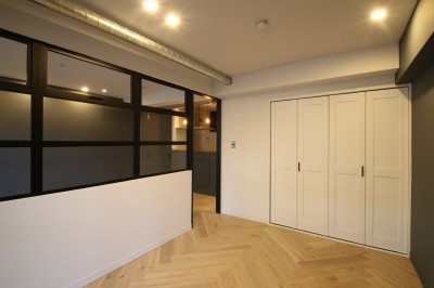 居室 (ヘリンボーンの床に、キッチンは塗装仕上げの木製モールディング)