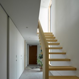 一階廊下．ヒノキ無垢材の階段と土間の連続のようなタイル床の対比 (目黒の家〜天空光を取り込む家〜)