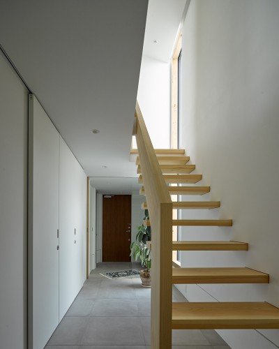 一階廊下．ヒノキ無垢材の階段と土間の連続のようなタイル床の対比 (目黒の家〜天空光を取り込む家〜)