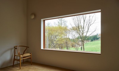 高山村の小さな家 (木製窓のフレームから借景の牧草地を見ています)