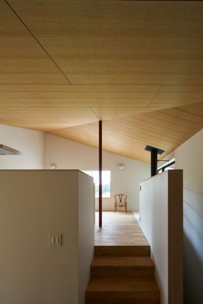 大空間を支える朱色の鉄骨柱と木合板仕上げの勾配天井 (高山村の小さな家)