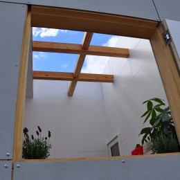 木造とは思えない開放的な空間と、いろんな使い方をできる十字のパーティションが印象的な住宅 (壁に囲われた屋外テラスの窓)
