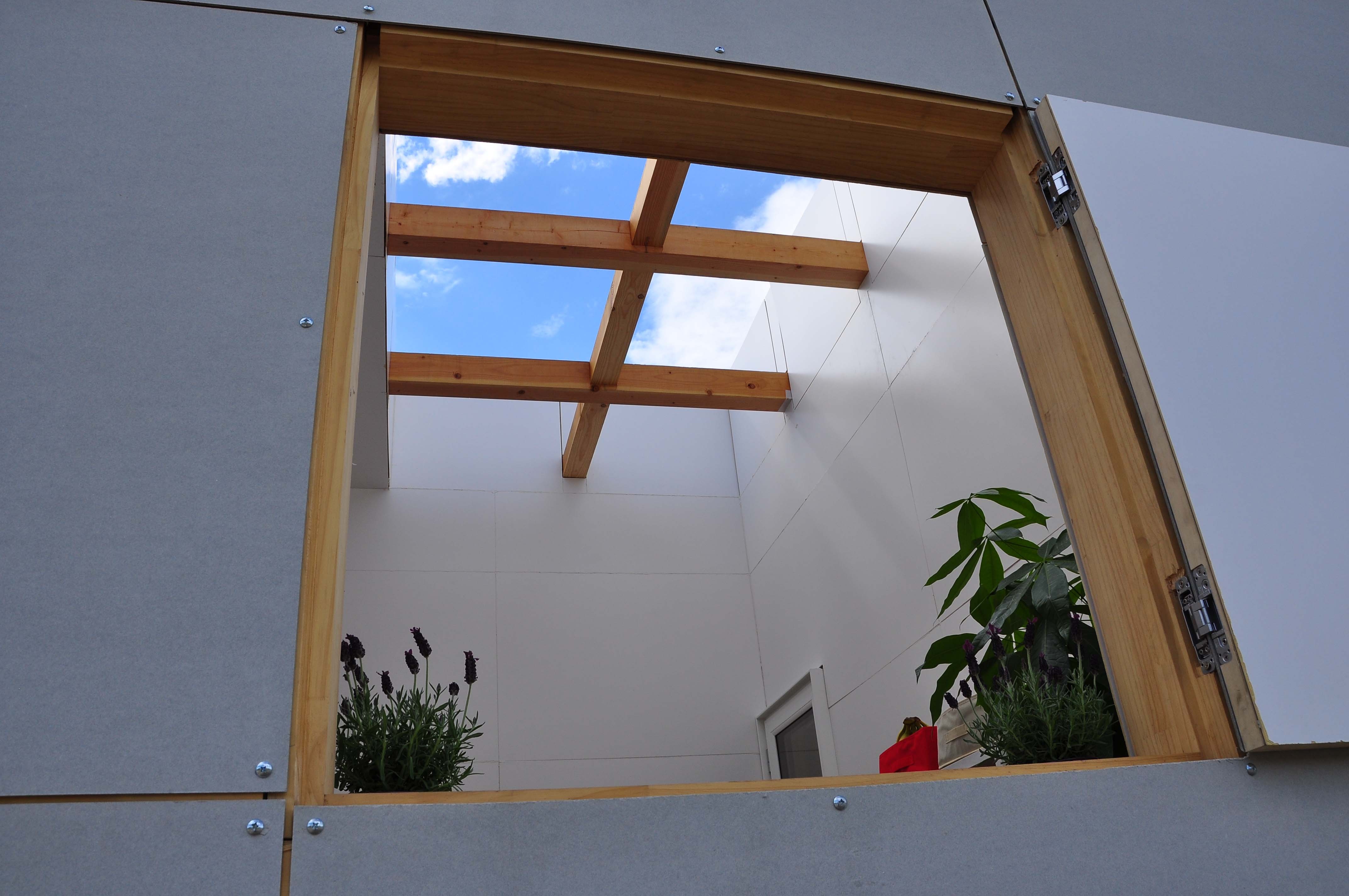 アウトドア事例：壁に囲われた屋外テラスの窓（木造とは思えない開放的な空間と、いろんな使い方をできる十字のパーティションが印象的な住宅）