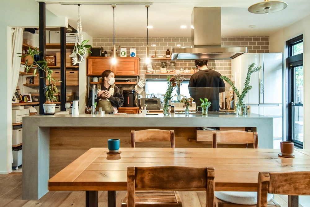 幸せな実家2世帯住宅リノベーション (モルタルのアイランドキッチンと木製のダイニングテーブル)
