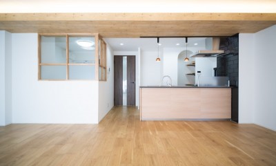 対面キッチンが主役！シックなデザインで統一感ある空間｜4人暮らし・126.06平米 (リビングからキッチンにかけて)