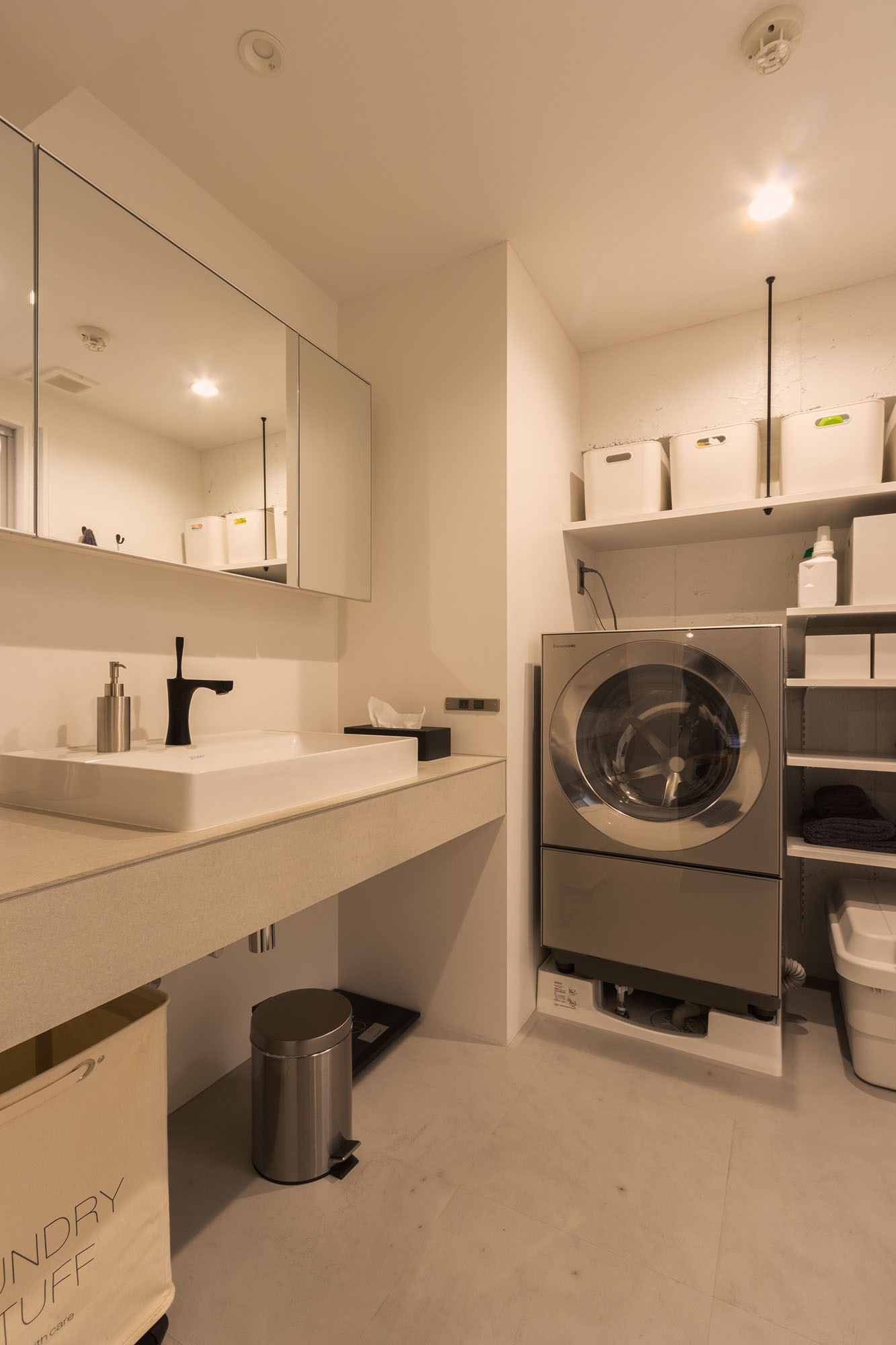 バス/トイレ事例：LDKと雰囲気をガラッと変え、白とグレーで統一した洗面室。生活用品などのストックは同じ種類のボックスに入れてすっきりと収納。（好きなモノを好きなだけ楽しむ、みんなの“行きつけ”の家）