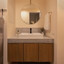 家具とイエ、両方が引き立つ家づくりの写真 モルタルの天板にリブパネルの戸板を組み合わせた造作洗面台。真鍮パーツがアクセントの清潔感のある空間。
