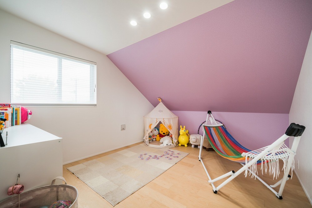子供部屋事例：子供部屋　屋根勾配がそのまま室内の天井になっているロフト風の空間です。アクセントの壁紙(ピンク)はお子さん自身で選定しました。（蓮田の家～大きな吹き抜けのある開放感～平屋をイメージしたすまい～）