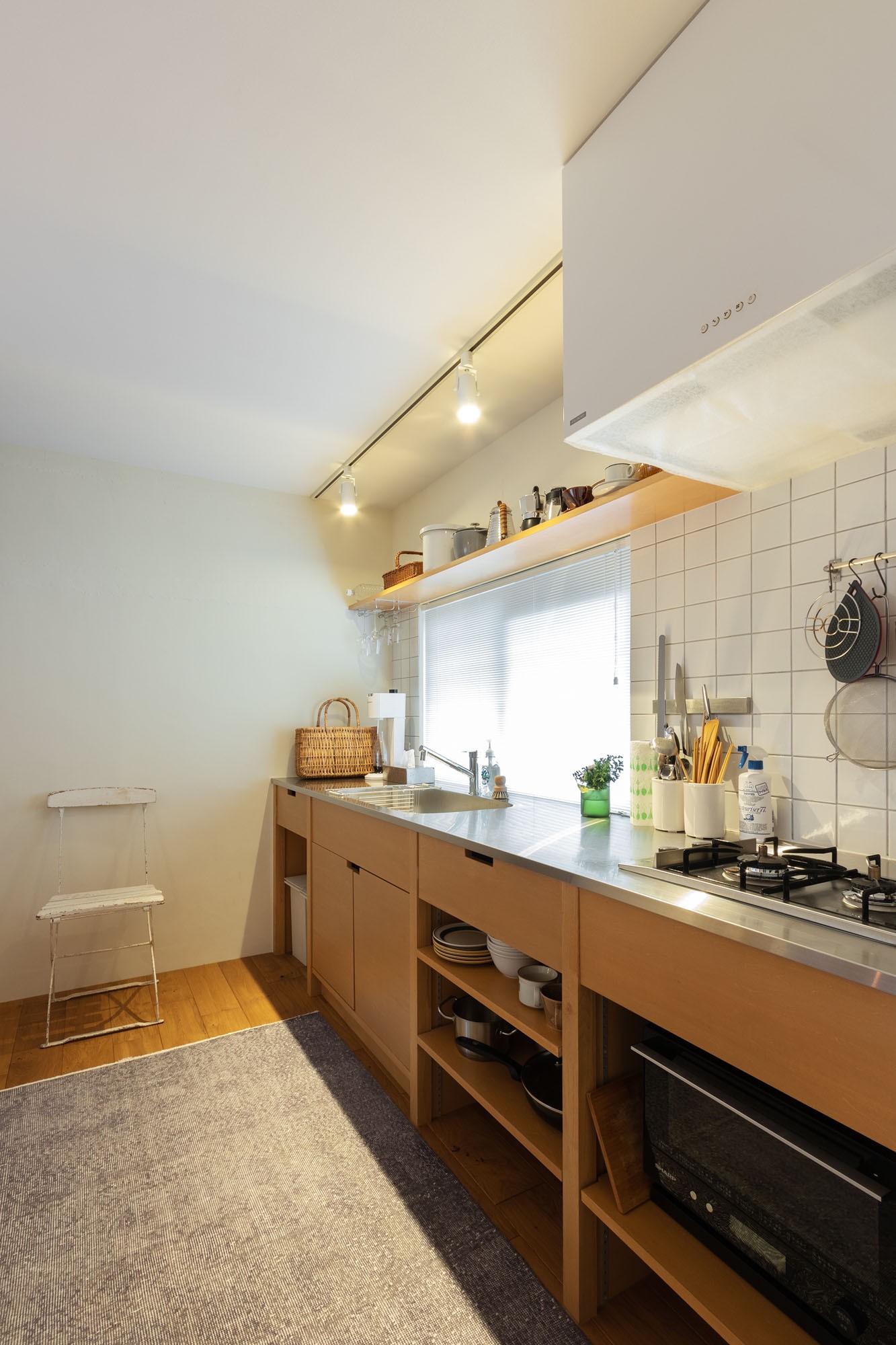 キッチン事例：キッチンはこんな奥とに壁付けでレイアウト。見せる収納に厳選した食器と調理器具が並ぶ。（ピットリビングのある“わたしサイズ”の家）