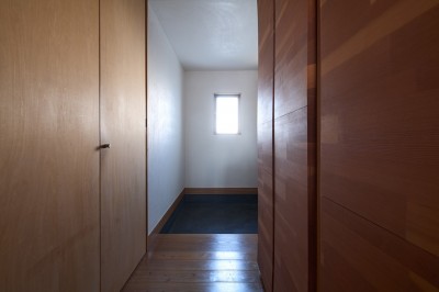 廊下から玄関を見る (長大な壁面収納のある集合住宅リノベーション)