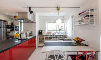 暮らしの背景としての白 (対面に換えた赤のキッチンに合わせて、椅子にもポイントを加えた、白ベースのダイニング)