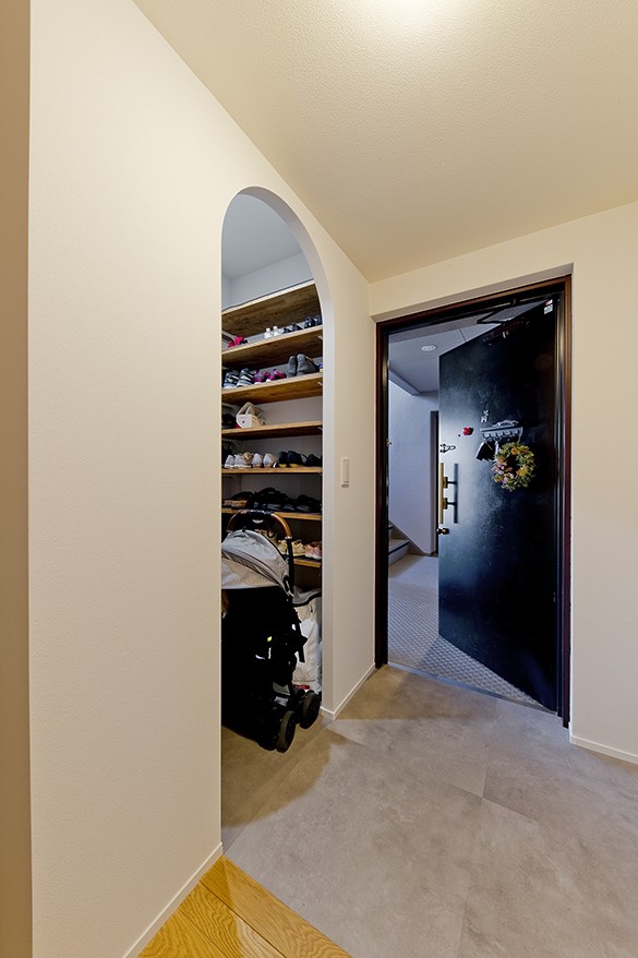 玄関事例：ベビーカーも置けるシューズクロークを併設。入口の開口はアーチ形に（デザインも機能性も大満足なお家に。子どもがぐるぐるかけまわる無垢オーク材の床が心地いい広々空間。）