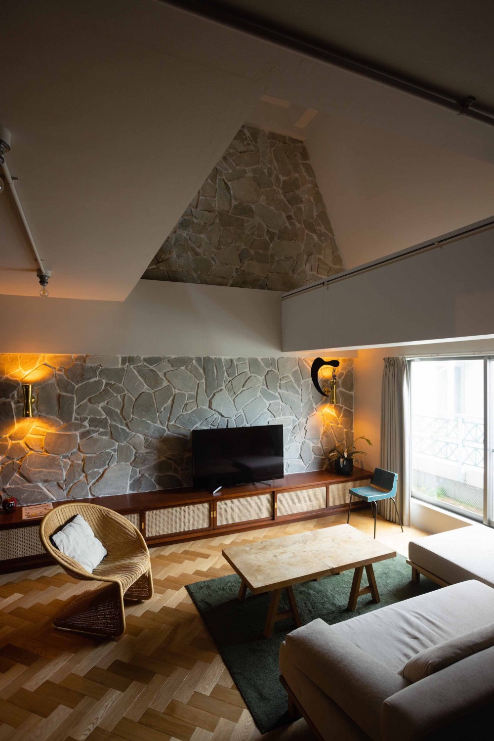 ヴィンテージ家具が似合うメゾネットの贅沢な空間 (一面の壁に天然石を張り込んだ吹き抜けリビング。)