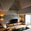 ヴィンテージ家具が似合うメゾネットの贅沢な空間の写真 一面の壁に天然石を張り込んだ吹き抜けリビング。