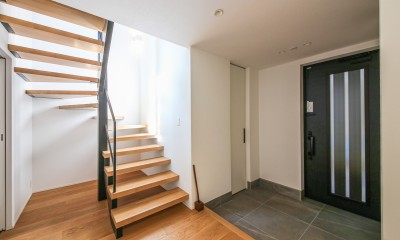 吹き抜けと空中回廊のある家／東京都目黒区 (階段ホールから光が射す玄関)