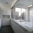 『公園を臨む家』公園を借景とする明るい住まいの写真 白いタイル張りのバスルーム