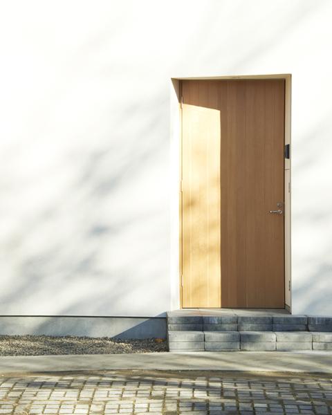 玄関事例：白い外壁に映える木製玄関ドア（木造町の離れ）