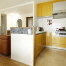 K邸・小さな個室と大きなリビング、心地のよい暮らし方の写真 ビタミンカラーのL字型対面式キッチン
